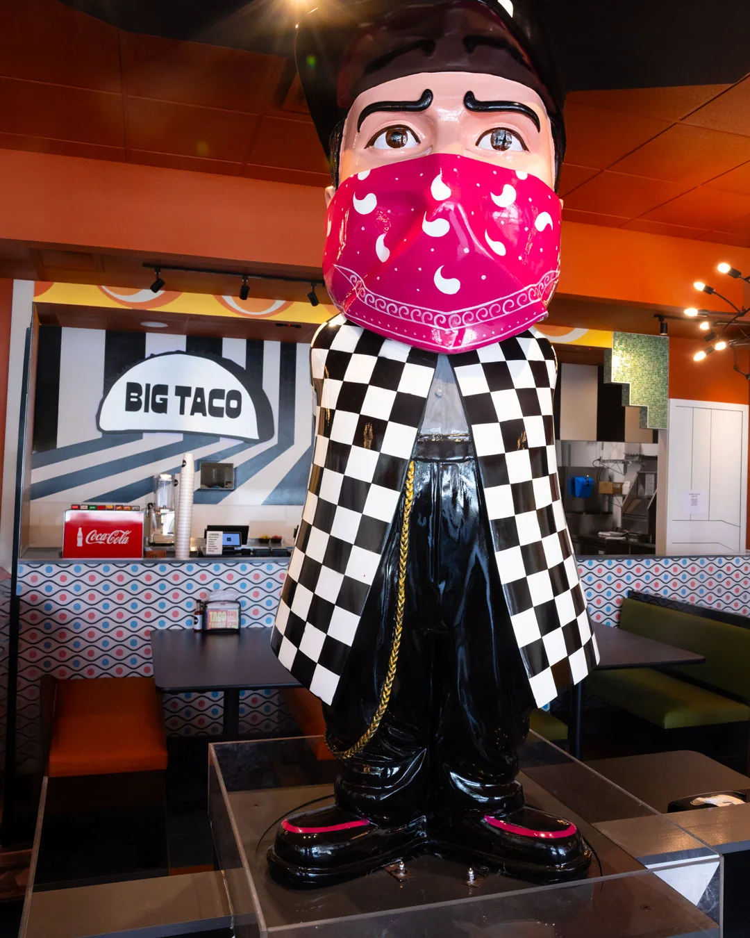 The dining room at Big Taco Oviedo, with the restaurant mascot statue in a pink bandana and the Big Taco mural behind